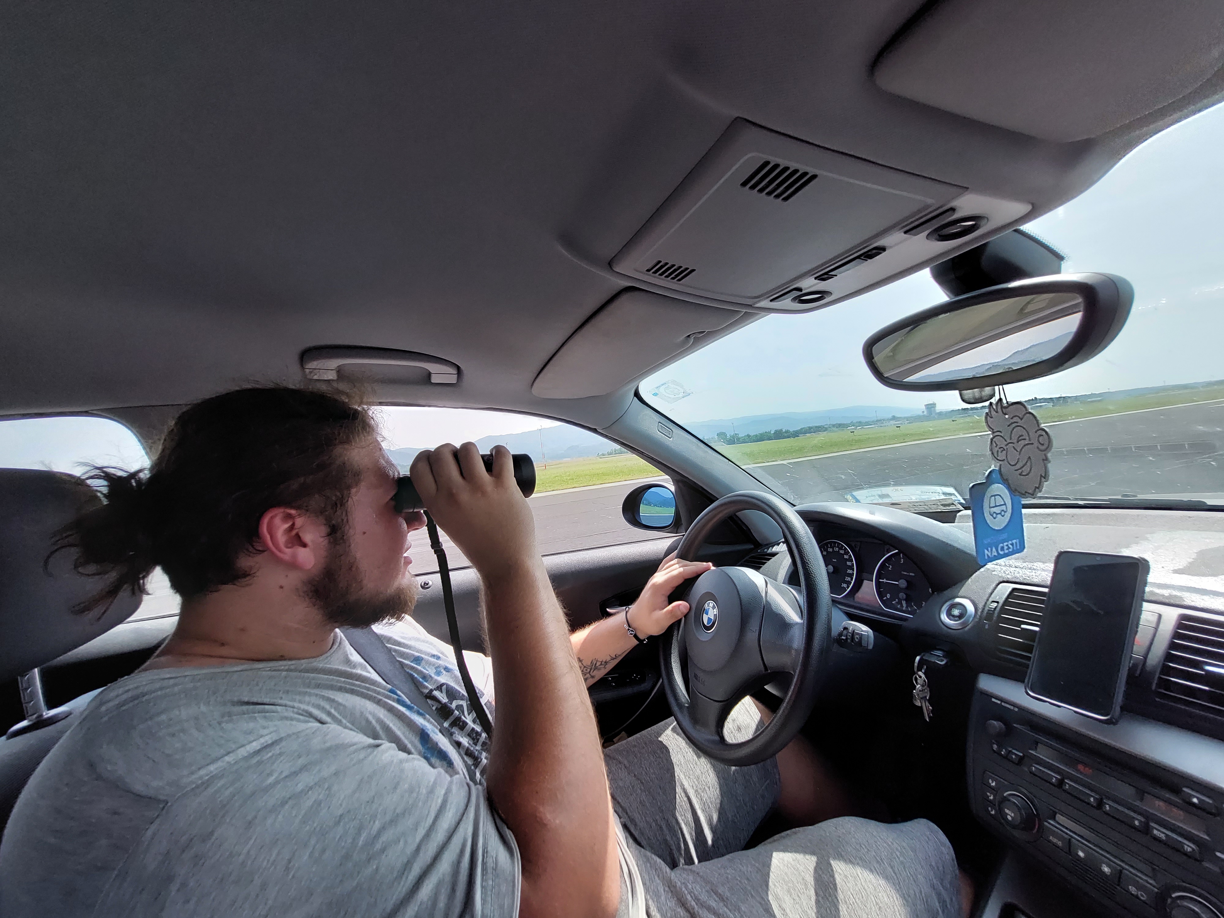 A person driving a car on inactive runway looking for our cansat in the surrounding fields